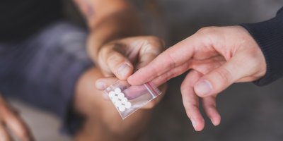 Dva muži si předávají sáček s pilulkami extáze