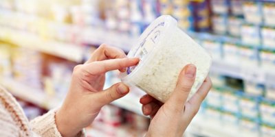 Ruka drží v supermarketu kelímek se sýrem cottage