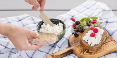 Ruce nabírají sýr cottage na chléb