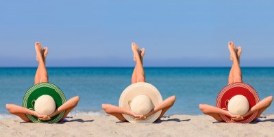 Tři ženy na pláži s klobouky