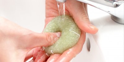 Člověk namáčí konjakovou houbičku proudem vody