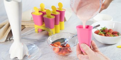 Člověk plní formičku na nanuk, mixér, metlička, jahody, pět formiček na nanuky