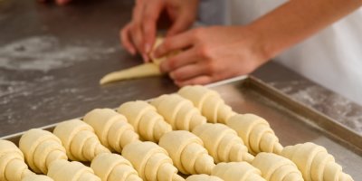 Člověk vyrábí rohlíky z těsta a pokládá na plech