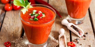 Gazpacho ozdobené nakrájenou okurkou, paprikou a ředkvičkou ve dvou sklenicích, koření