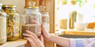 Žena dává jáhly ve sklenici do regálu