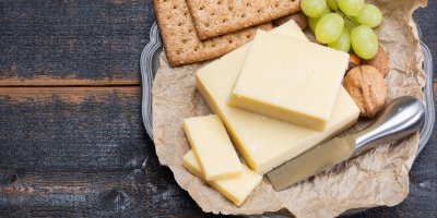 Kousky sýru, krekry, vlašské ořechy, hroznové víno na tácu