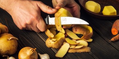 Ruce nožem loupou brambor