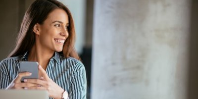 Usmívající se žena s mobilním telefonem v ruce