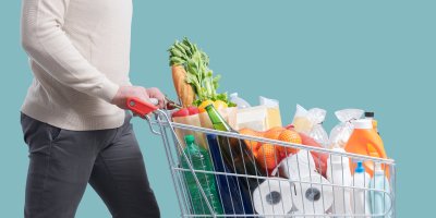 Muž tlačí nákupní vozík, ve kterém jsou potraviny a drogistické zboží