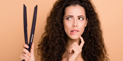 Žena drží žehličku na vlasy