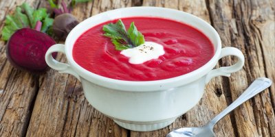 Krémová polévka z řepy ozdobená smetanou a bylinkami, rozkrojená řepa, lžíce