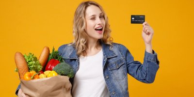 Paní drží nákup a platební kartu