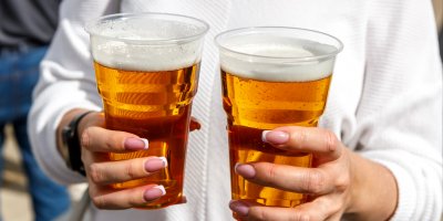 Žena držící dva plastové kelímky s pivem