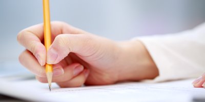 Člověk píše na papír obyčejnou tužkou