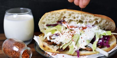 Kebab se zeleninou a dresinkem v pita chlebu, ayran ve sklenici, koření