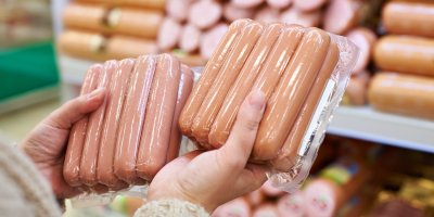 Ruce držící dva balíčky vakuově balených párků