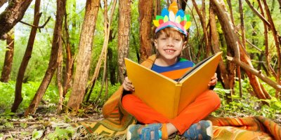 Kluk s indiánskou čelenkou čte knihu