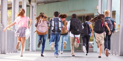 Skupina běžících dětí se školními batohy na zádech