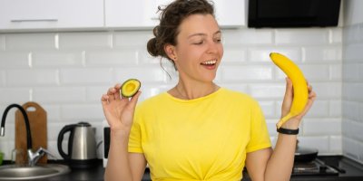 Žena drží avokádo a banán