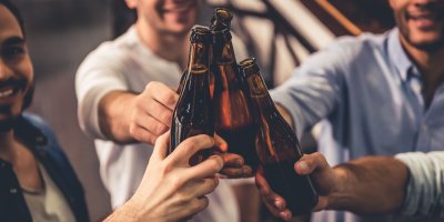 Skupina mužů si přiťukává pivními lahvemi