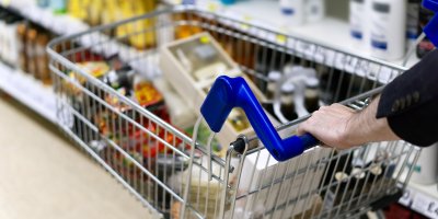 Člověk v uličce supermarketu tlačí plný nákupní vozík