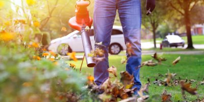 Muž fouká listí zahradním vysavačem