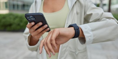 Žena si prohlíží chytré hodinky a smartphone