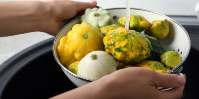 Člověk oplachuje různě zbarvené patizony v misce