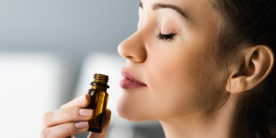 Mladá žena čichá k lahvičce s éterickým olejem