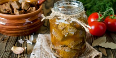 Zavařovací sklenice naplněná masem, rajčata, česnek