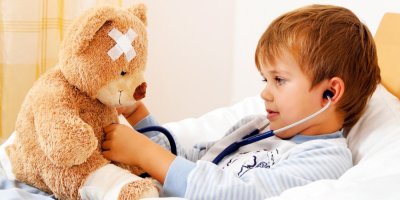 Chlapeček v posteli vyšetřuje medvídka s náplastí