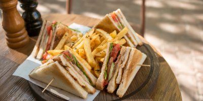 Dřevěný tác s Club sendvičem a hranolky