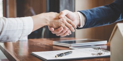 Dva lidé si potřásají rukou nad uzavřenou smlouvou