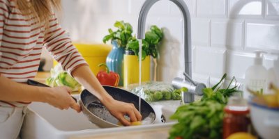 Žena umývá ve dřezu pánev