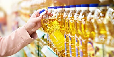 Žena si bere olej z regálu v supermarketu