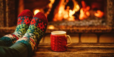 Detail noh v ponožkách před hořícím krbem