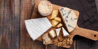 Prkénko, na kterém jsou různé druhy sýrů a vlašské ořechy