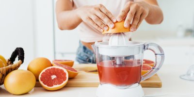 Žena vymačkává šťávu z grepů pomocí manuálního lisu