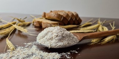 Dřevěná lžíce s moukou, žitné klasy a plátky chleba