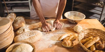 Pekař hněte těsto na pracovní desce s pečivem