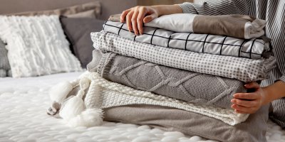 Hromádka složených dek rozličných odstínů a materiálů