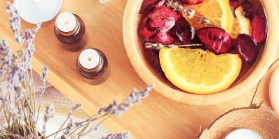 V míse s esenciálním olejem se louhují růže a pomeranče, vedle jsou dva olejíčky a levandule