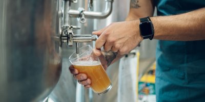 Muž čepuje pivo z tanku do sklenice