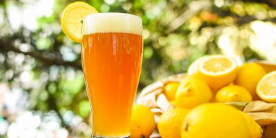 Sklenice ovocného, citronového radleru s miskou citronů v pozadí