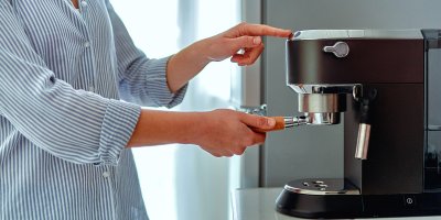 Žena připravuje kávu v kávovaru