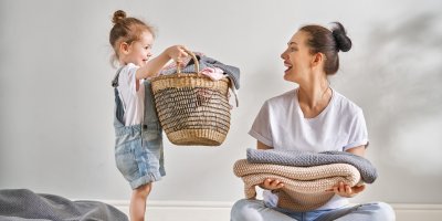 Maminka s dcerou a hromadou prádla v košíku
