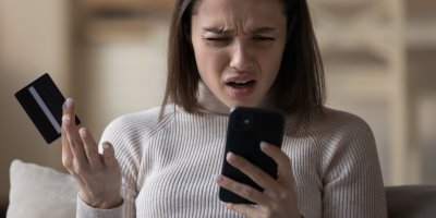 Zoufalá žena s mobilním telefonem a kreditní kartou