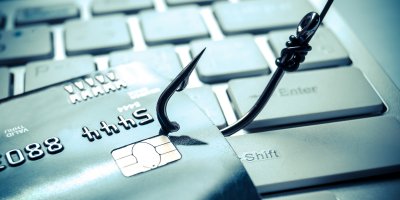 Kreditní karta nad notebookem chycená rybářským háčkem