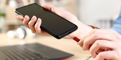 Člověk zapojuje nabíječku s konektorem USB-C do mobilního telefonu