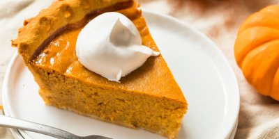 Kousek dýňového koláče se zakysanou smetanou na bílém talířku